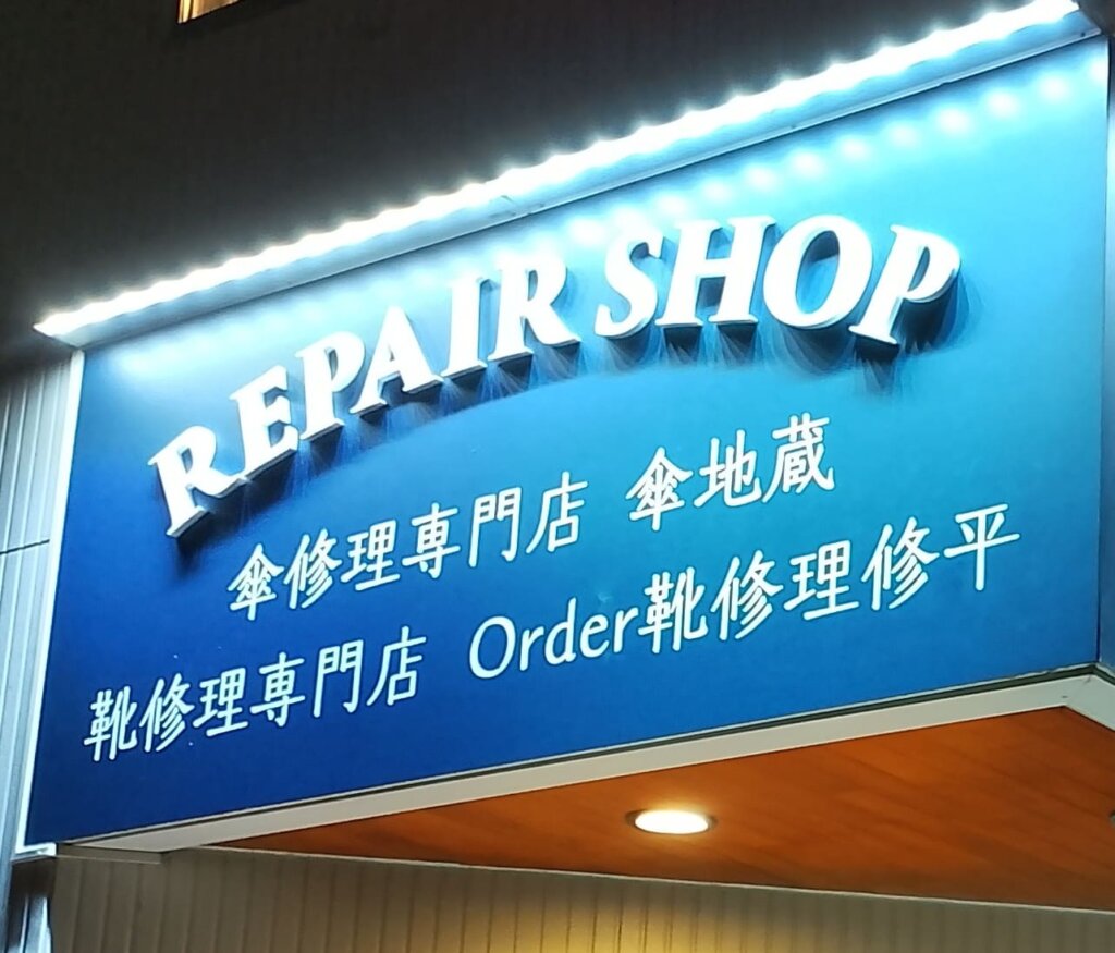 横浜・山手の靴修理専門店Order靴修理修平の店舗外観。青い看板に『REPAIR SHOP 靴修理専門店 Order靴修理修平』と書かれた夜のライトアップ看板。