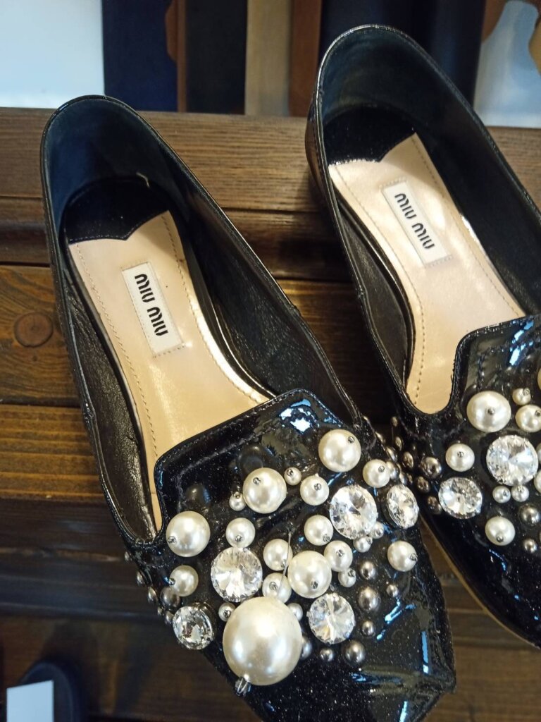 miu miu パンプスのビジューが緩み外れかけている修理前のアップ画像。飾り部分にズレと破損が見られる。