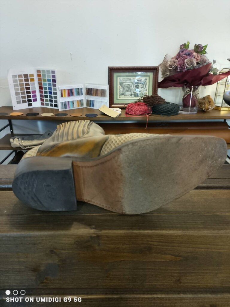 「ウエスタンブーツを寝かせた構図で撮影したビフォー写真。アウトソール全体の摩耗・表面劣化がはっきり確認できる状態。」