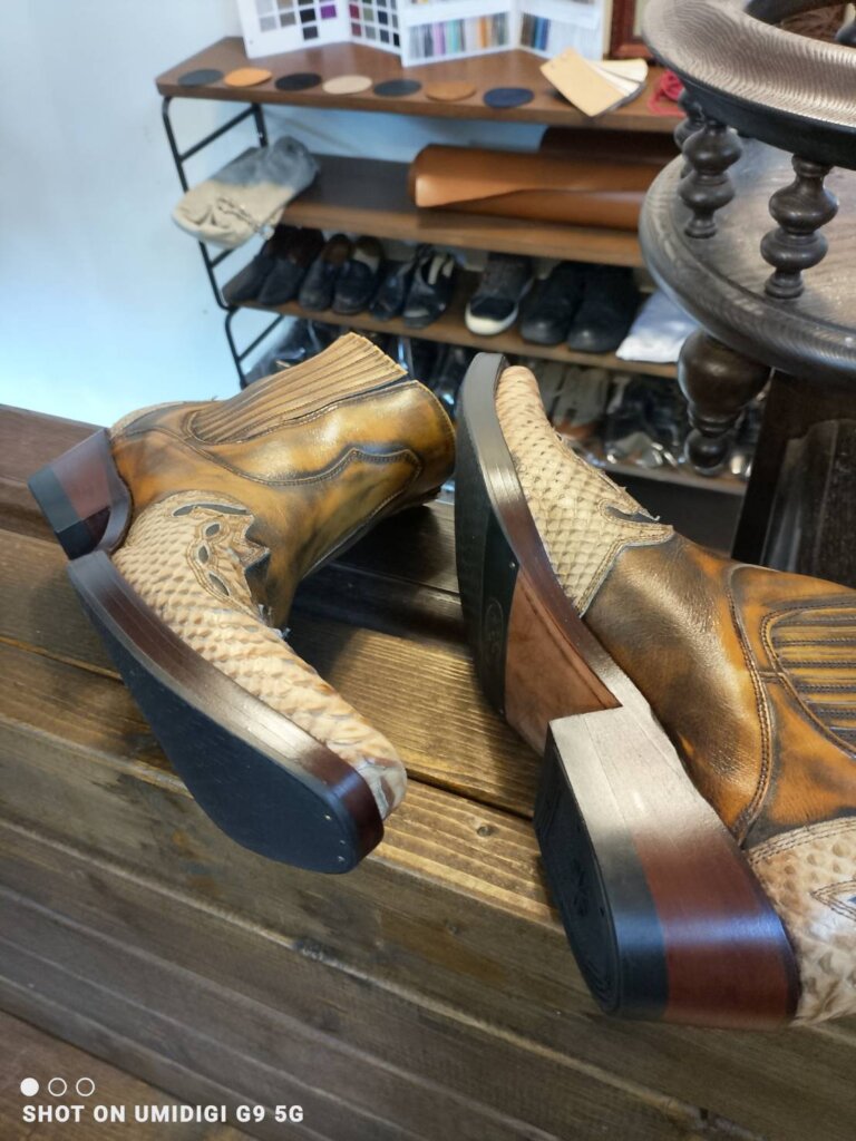 横浜 靴修理「横浜でお預かりしたウエスタンブーツのビフォー写真。正面から撮影した全体構図で、かかと摩耗とレザーの経年変化が確認できる状態。」